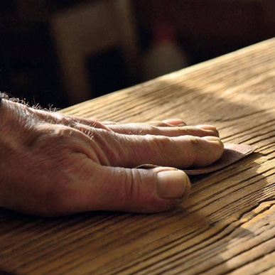 Craftsman's hand feeling the carved texture of an oak wood board