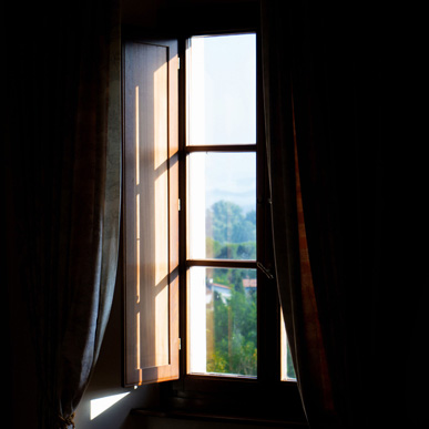 Filtered sunlight entering a dark Tuscan interior through a half-closed shutter