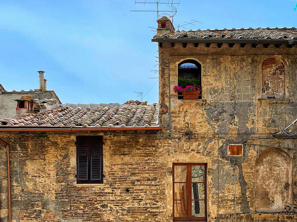 Historic Tuscan village house with a richly detailed stone and terracotta facade and varied windows
